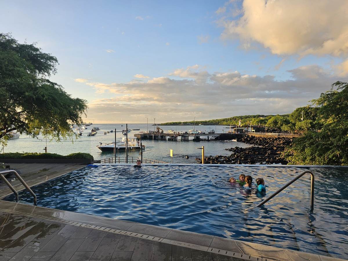Infinity pool overlooking the San Cristóbal harbor at sunset, with kids swimming