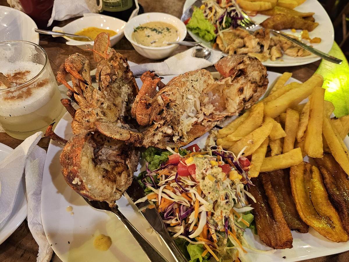 A seafood platter with grilled lobster, fries, and plantains