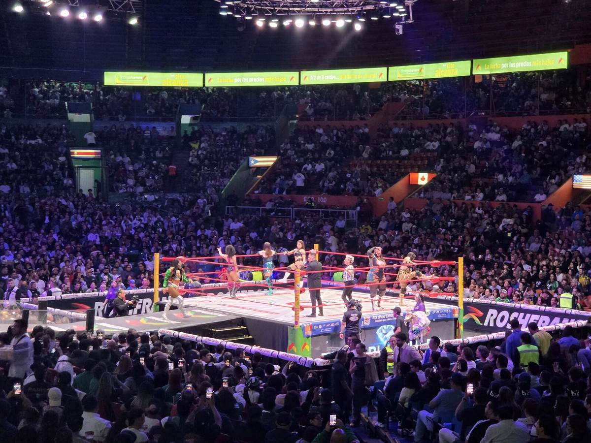 A lucha libre wrestling match in the ring at Arena Mexico, with a packed crowd