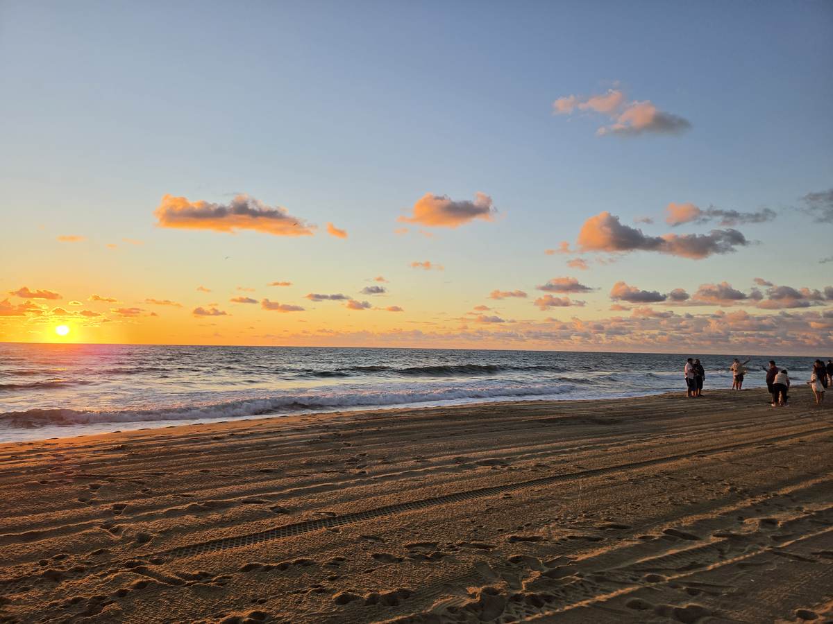 Sunset over the ocean at Virginia Beach with people gathered on the sand